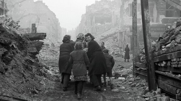 Жители Берлина возвращаются домой по заваленной обломками улице