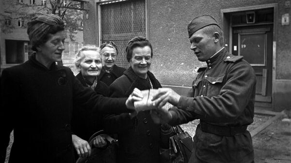 Советский солдат раздает хлеб женщинам Берлина