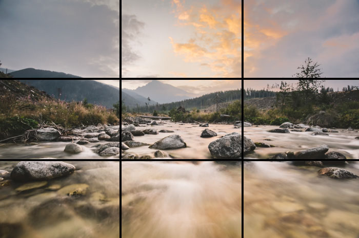 A landscape scene focusing on soft misty flowing river with the rule of thirds grid overlayed
