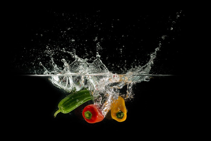 high speed shot of vegetables splashing into water