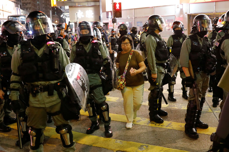 © Reuters. A woman makes her way between riot police officers as they try to disperse protesters gathering for a demonstration in Hong Kong
