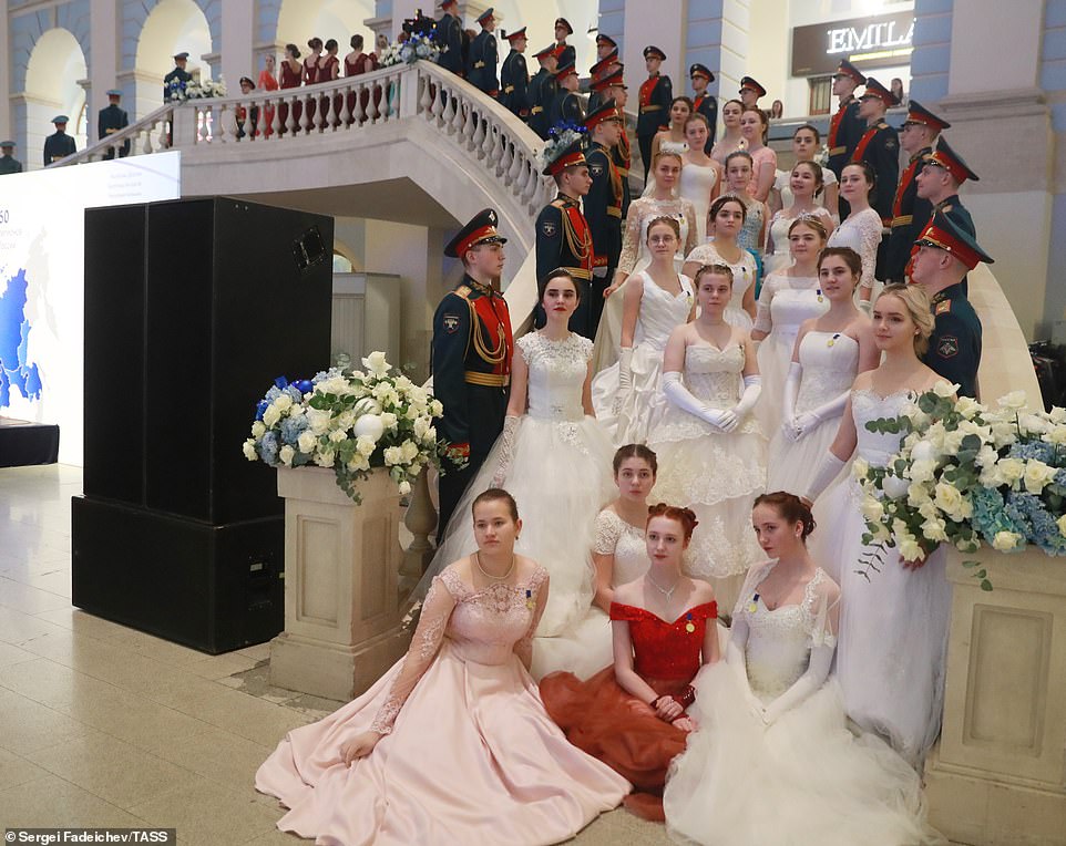 Male cadets line the stairs while their ballgown-clad partners pose for a photograph on the staircase at the International Kremlin Cadet ball 