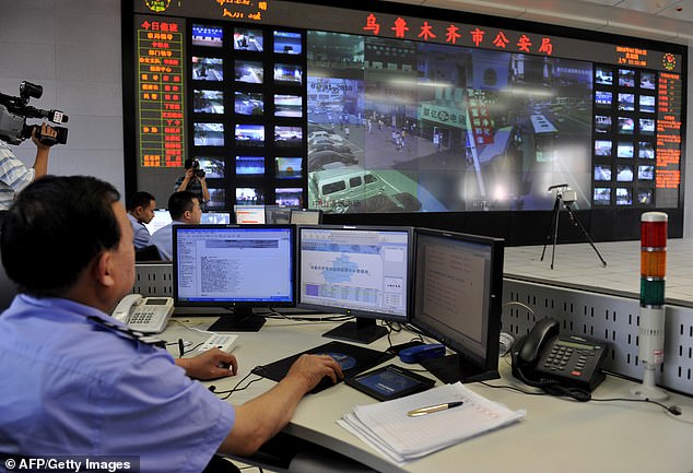 A policemen watch screens showing public areas monitored by security cameras in Urumqi