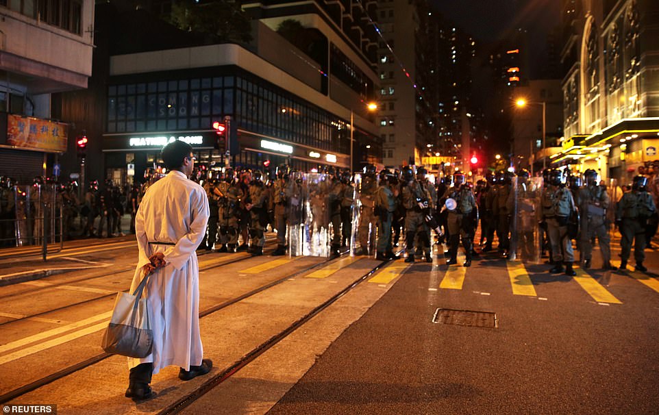 The priest calmly walked towards the row of police during the nighttime protests which have now spanned several weeks