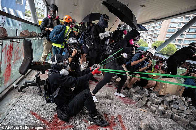 Armed: Hong Kong protesters fire a catapult at police during a protest at the City University today, on another day of clashes following severe violence on Monday