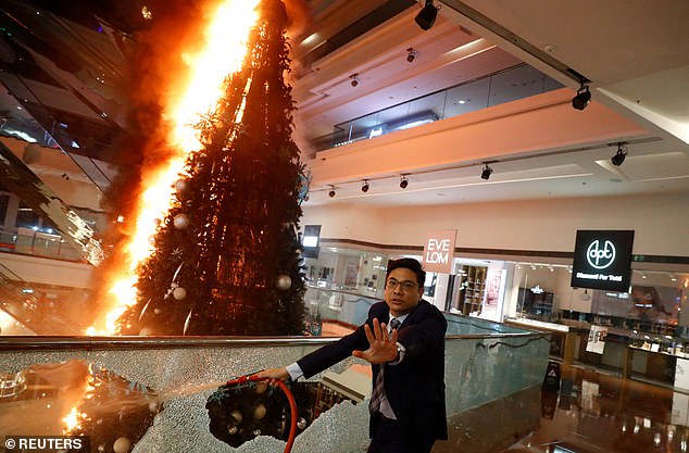 A man tries to extinguish a burning Christmas tree at a mall in Kowloon Tong. The financial hub was once again rocked by anti-government protests today after yesterday