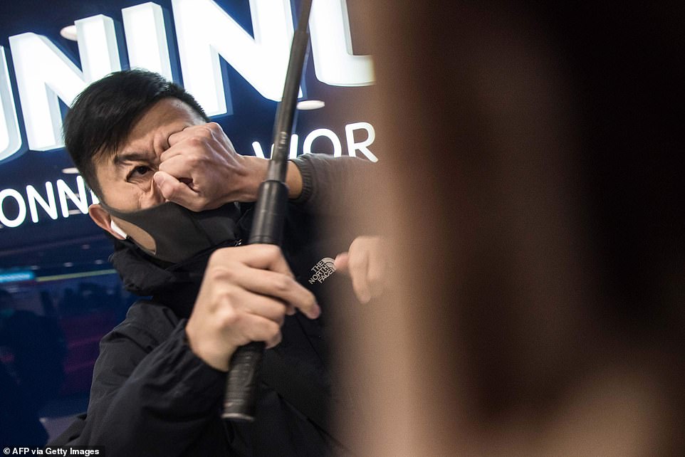 A plainclothes police officer can be seen as a pro-democracy protester strikes him in the face during a rally inside a shopping mall in Sheung Shui in Hong Kong today
