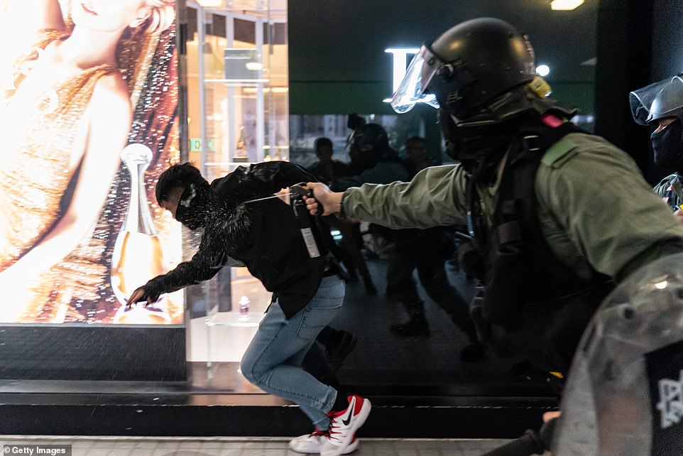 A riot policeman fires a blast of pepper spray at a protester at the Sheung Shui district shopping mall earlier today