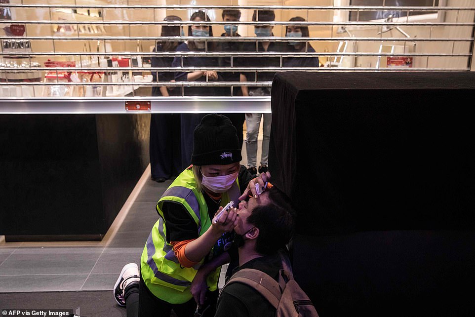 Employees stand inside their closed store as a medic treats a man who was hit by pepper spray deployed by police during a pro-democracy protest inside a shopping mall in Sheung Shui in Hong Kong today