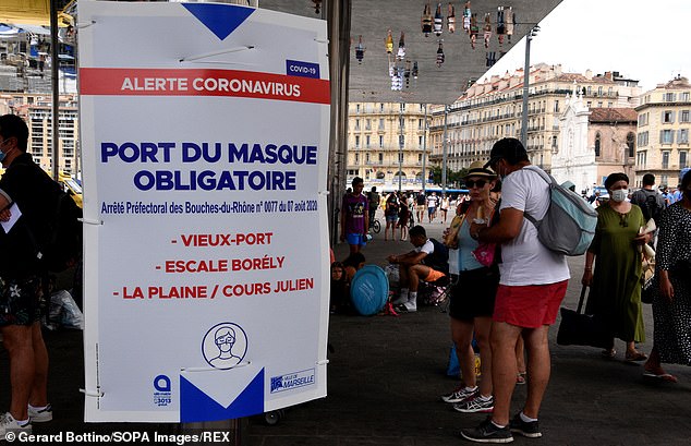 In the Old Port area of Marseille a sign informs passers-by to wear a face in an effort to reduce the number of infections