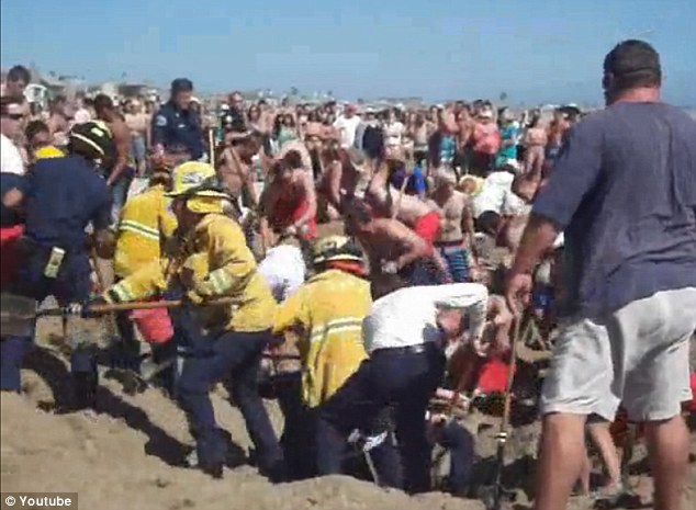 Desperate: People on the beach dig in to try to save the boy, shovelling away the sand