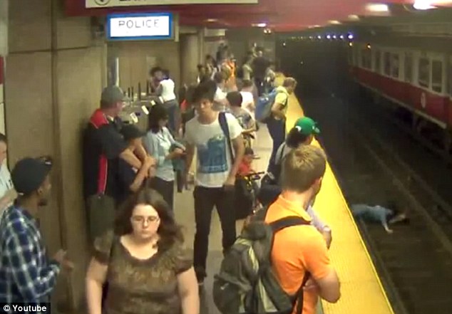 Sudden: Bystanders on the Greater Boston subway line stare in surprise as the woman and child lie on the rails