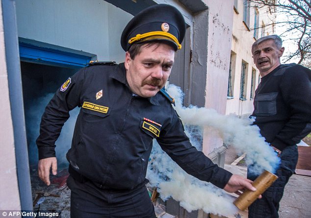 Smoke screen: A Ukrainian serviceman at a separate base in Novofedorivka tires to ward off Russian forces with a smoke grenade