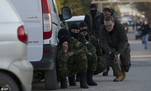Ready to attack: Armed men crouch behind a van just before charging into the base, where a stand-off has been developing for weeks
