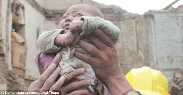 Saved: The baby boy, who emerged from the wreckage covered in dust, was miraculously found amid the devastation by rescue workers who heard the infant