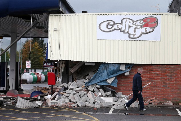 The officer sustained serious head injuries when low-loader truck ploughed into him at high speeds as he approached it on foot in Co. Armagh, Northern Ireland. Pictured, the damaged wall of the petrol station after the ATM was ripped out