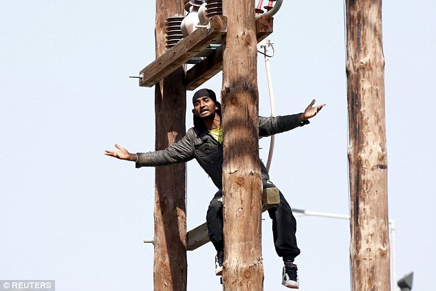 A Pakistani migrant climbs an electricity pole during a demonstration inside the Moria registration centre on the Greek island of Lesbos on Wednesday