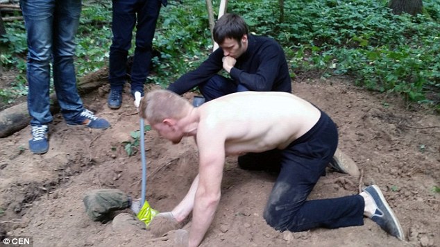 Buried alive: A volunteer buried in the earth breathes through a blue pipe to survive