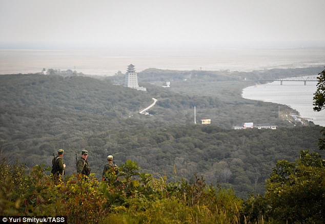 Russian soldiers in their uniform and carrying rifles look south to the direction of North Korea