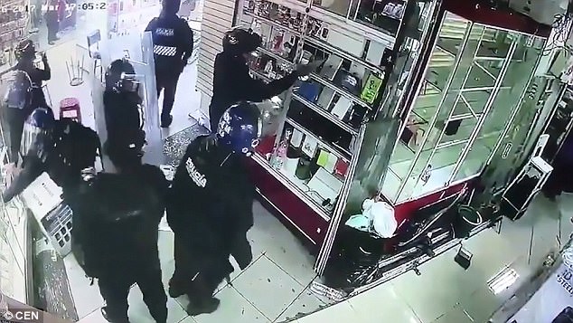 The clip appears to show that two officers (pictured) started the looting by helping themselves to the store