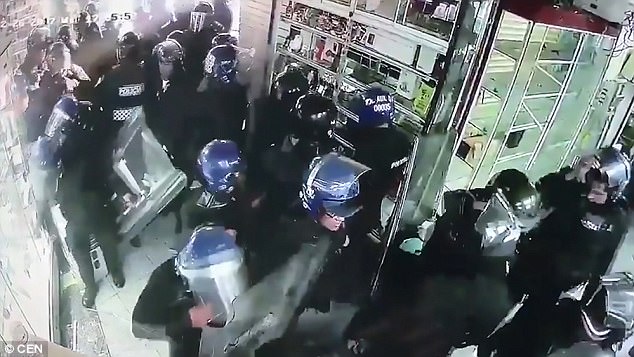 This is the shocking moment (pictured) riot police were caught on camera stealing from a mobile phone shop in Mexico