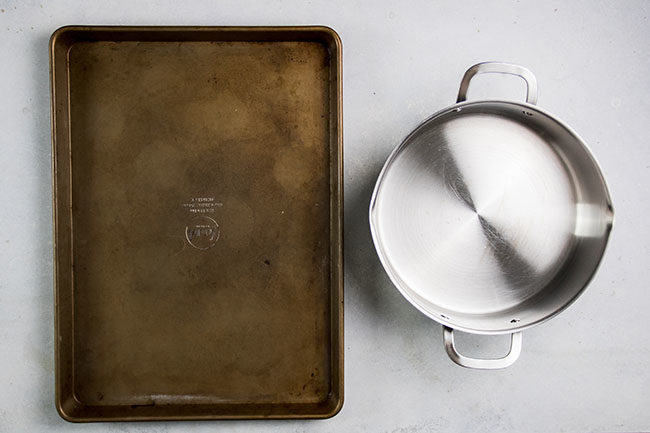 overhead photo of a baking sheet next to a stainless steel pot