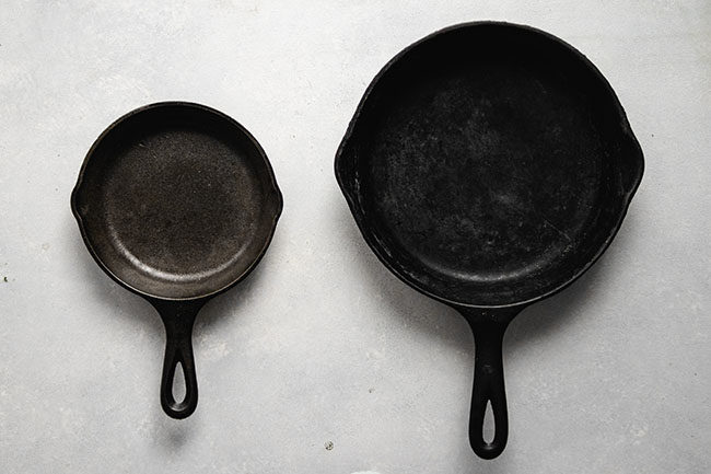 overhead photo of a large cast iron skillet next to a small cast iron skillet