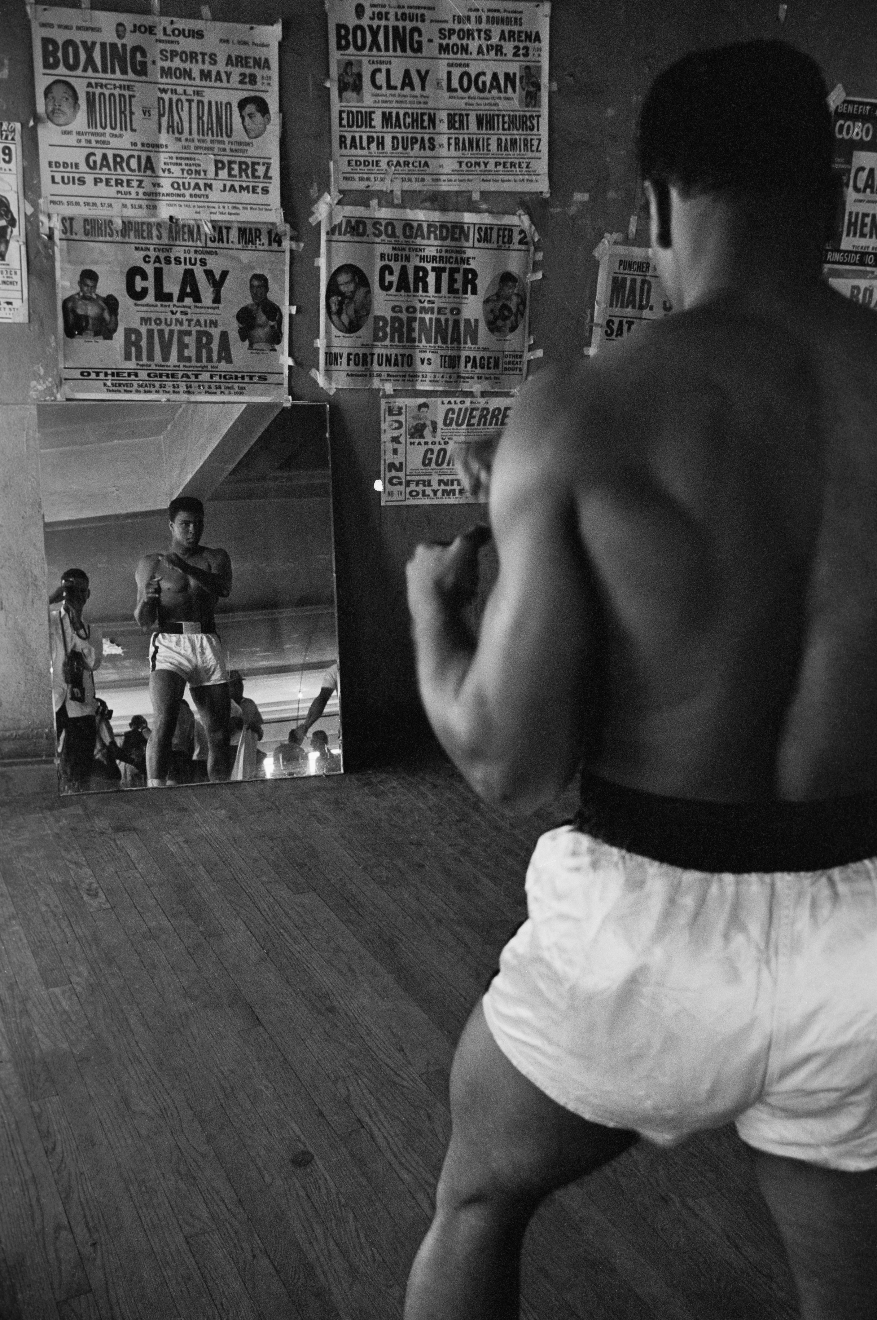 Heavyweight contender Cassius Clay watches himself in a mirror at his training gym as he prepares for a title fight with champion Sonny Liston. 