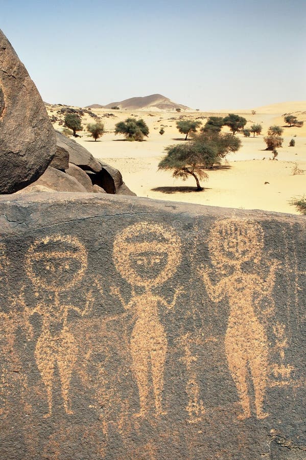 Ancient rock art in Sahara depicting three figures royalty free stock images