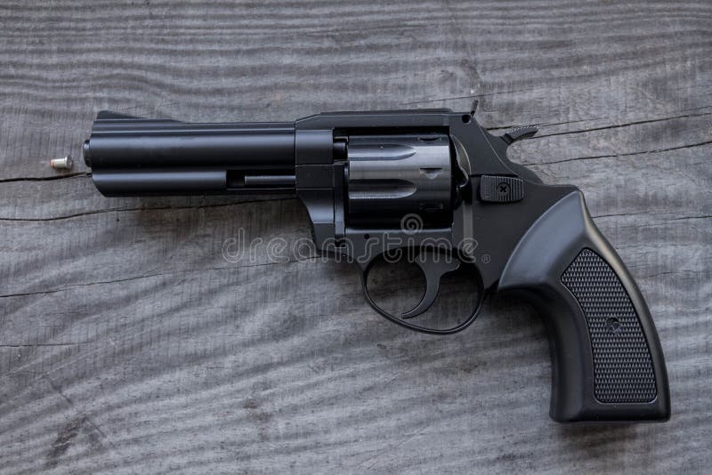 Black revolver with a bullet. Black revolver with a drum on a wooden background stock image