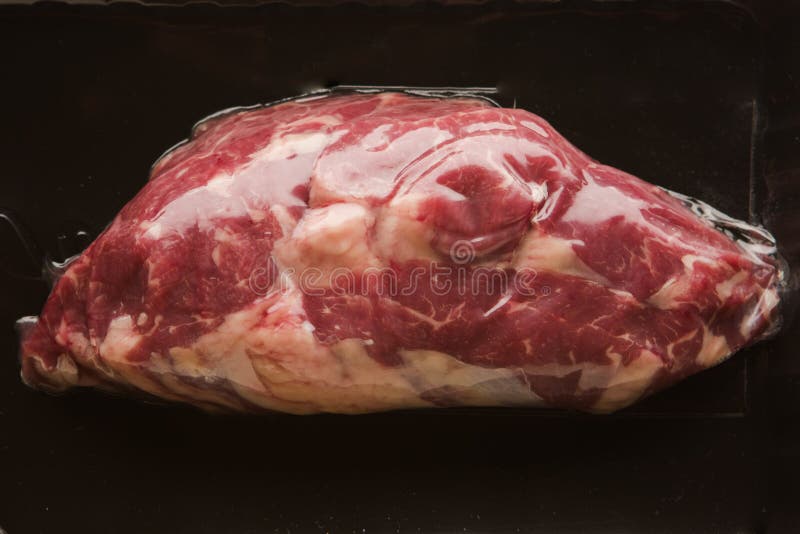 Fresh vacuum packed meat on black background royalty free stock photography