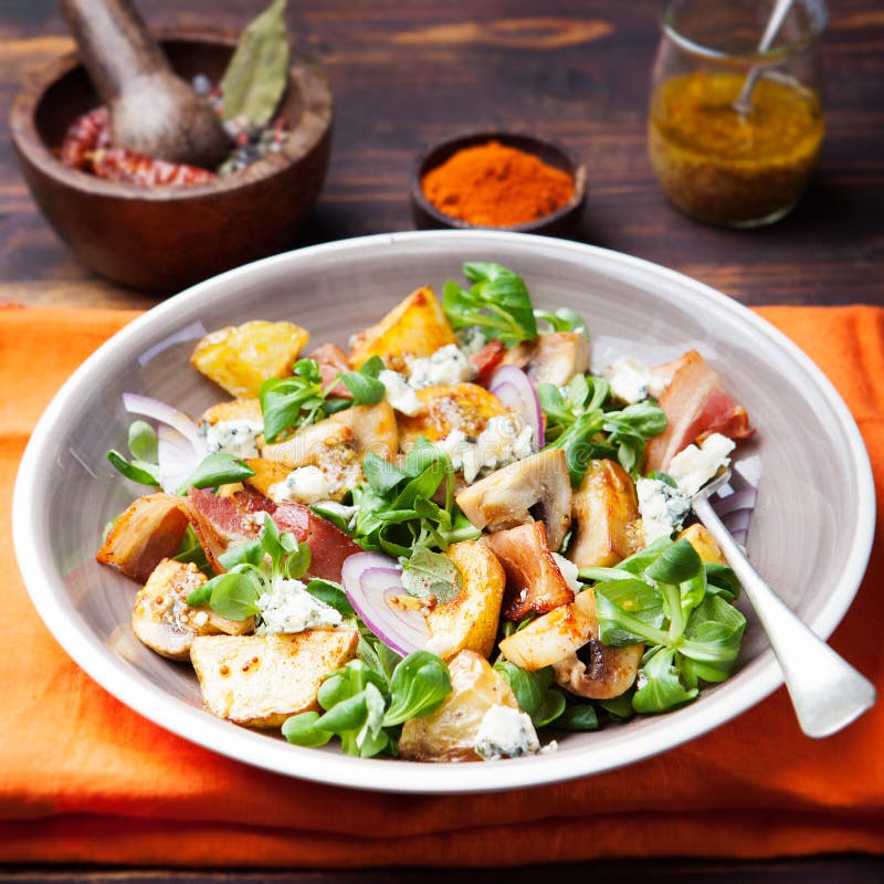 Potato salad with bacon, mushroom on orange napkin Wooden background stock photo