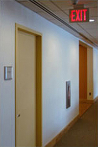 photo of a hallway with an opening a closed door with an exit sign
