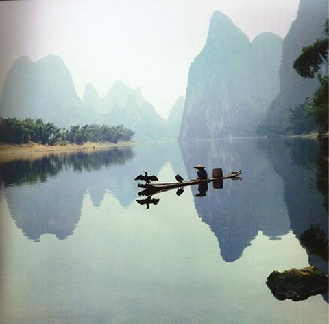 Фотография умиротворенного пейзажа: лодка плывущая по воде на фоне гор