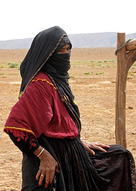 Saharan woman, traditionally dressed, at communal well.