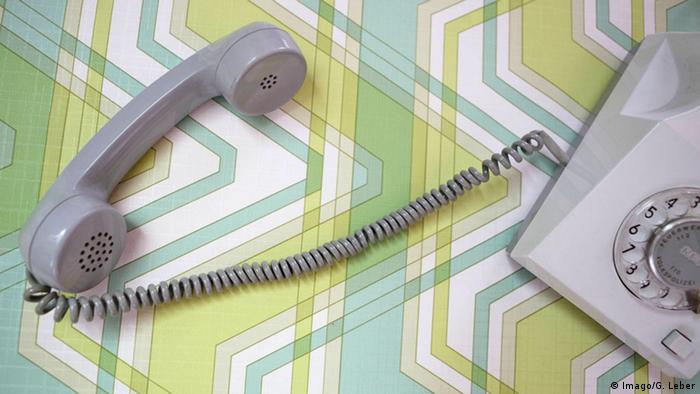 A landline phone sitting on a green tablecloth