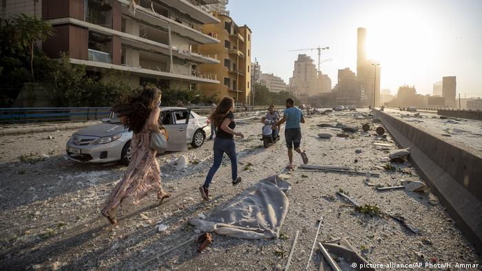 People in Beirut run through the rubble in the explosion aftermath 